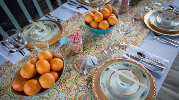 Bowls of oranges, vintage plates and paper fortune cookies set up as a Chinese New Year tablescape