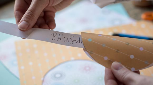 Inserting paper with a hand written name into a paper fortune cookie
