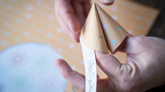 Pinching together a paper fortune cookie with the hand written name tag